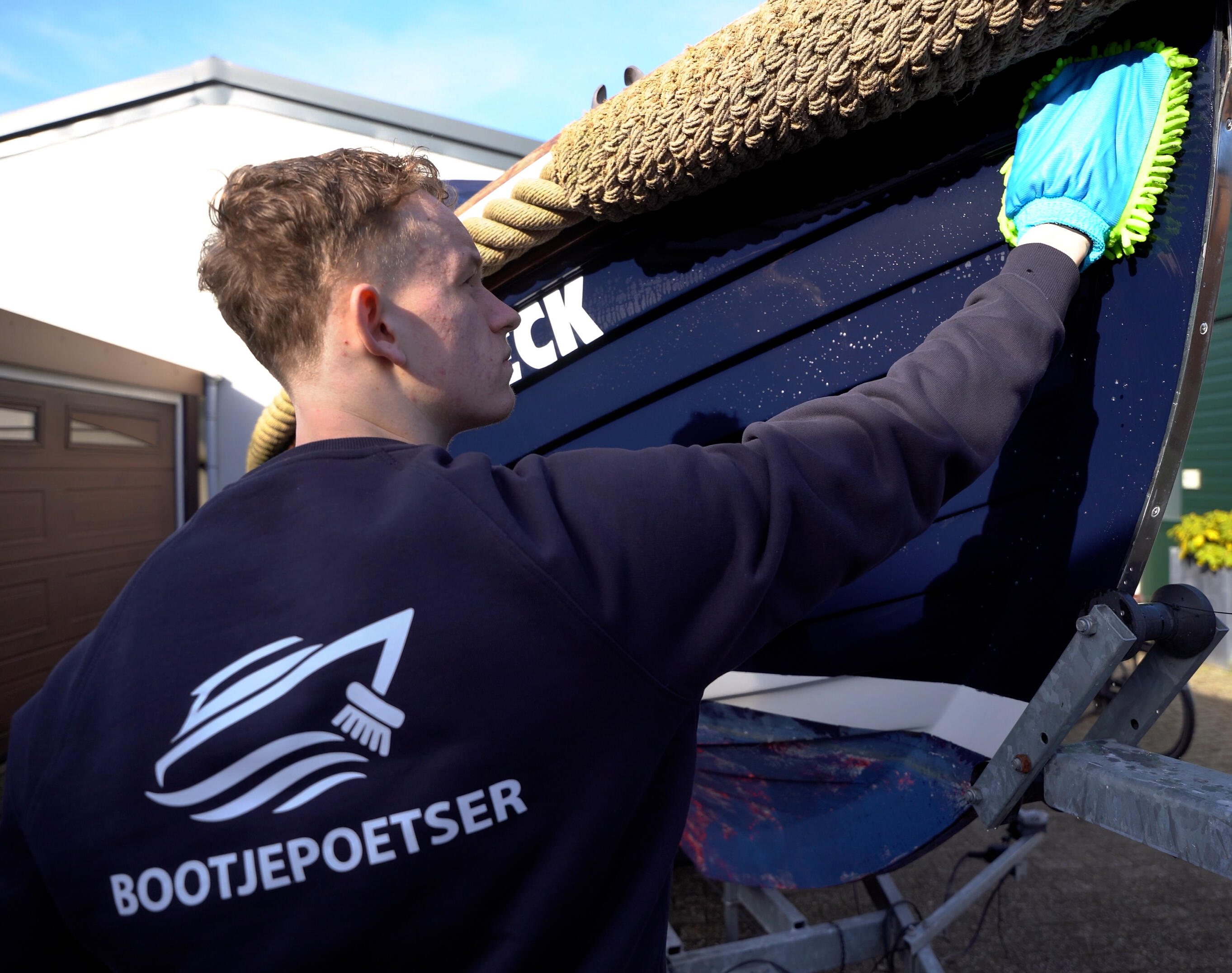 Professionele bootreiniger polijst een boot op locatie in de haven